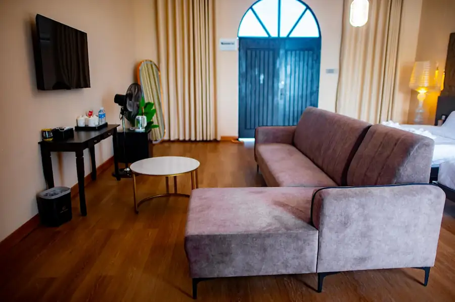 Comfortable living area inside the Bedroom Deluxe Two Queen Beds at Turtle Seaweed Resort featuring a large grey sectional sofa, TV, and arched double doors.